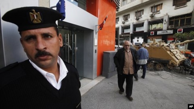 An Egyptian policeman stands guard outside a bank in Cairo February 20, 2011