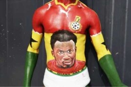 A Ghanaian football fan shows off his body painting, containing the image of star player Michael Essien