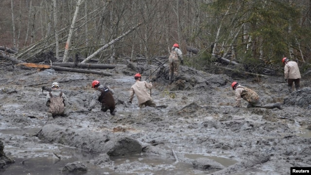Rescue workers make their way through the mud and wreckage left behind by Saturday's mudslide as they look for signs of missing people, in Oso, Washington, March 27, 2014.