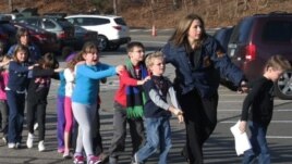 Connecticut State Police lead a line of children from the Sandy Hook Elementary School in Newtown, Conn. on Friday, Dec. 14, 2012 after a shooting at the school. (AP Photo/Newtown Bee, Shannon Hicks)