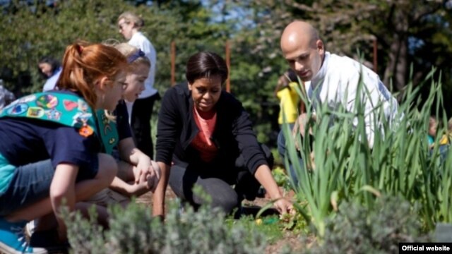 La primera dama junto a su asesor en las iniciativas de alimentación suladable, Sam Kass y una estudiante en el jardín presidencial.