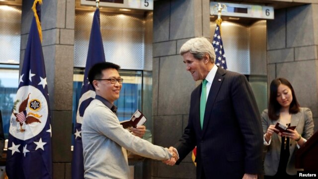  2014年11月12日，美国IBM公司雇员杨波（音译）在美国驻华使馆获得有效期为十年的签证，成为第一获得这样的中国人。图为美国国务卿与杨波握手。