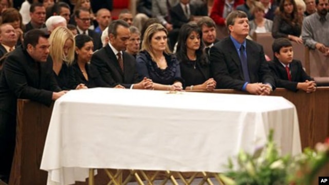 Family, including mother Roxanna Green, third from right, father John Green, second from right, and son Dallas Green, right, kneel in prayer behind the casket during the funeral of his daughter, 9-year-old Christina Taylor Green, in Tucson, Arizona, 13 Ja