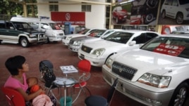 A potential customer breastfeeds her baby a saloon for newly imported cars in Rangoon.