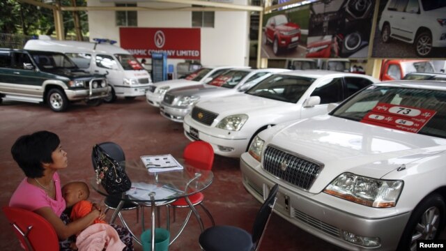 A potential customer breastfeeds her baby a saloon for newly imported cars in Rangoon.
