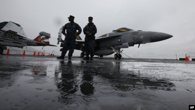 U.S. Navy deck crew members stand in front of an F/A-18 fighter jet on the aircraft carrier USS George Washington in Hong Kong, November 9, 2011. 