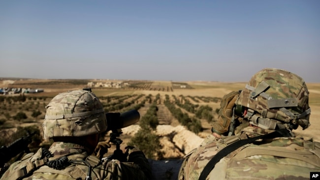Soldados estadounidenses observan hacia la frontera con Turquía, en Manbij, al norte de Siria.