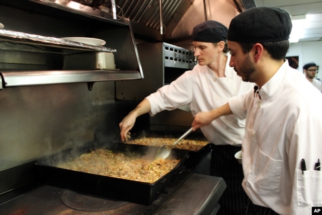 Sous chefs Adan Franco, right, and Casey Davison of the Sanford Restaurant season and stir cassoulet, to be delivered to the Guest House homeless shelter in Milwaukee, Dec. 8, 2015.