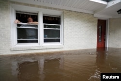 Obrad Gavrilovic mira desde la ventana de su casa inundada mientras considera si debe evacuar la vivienda junto con su esposa y mascotas, en tanto el agua continúa subiendo en Bolivia, Carolina del Norte. 15 de septiembre de 2018.