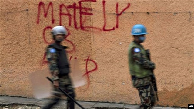 U.N. peacekeepers walk next to a wall with a graffiti in support of presidential candidate Michel Martelly at the Petionville neighborhood in Port-au-Prince, 12 Dec 2010