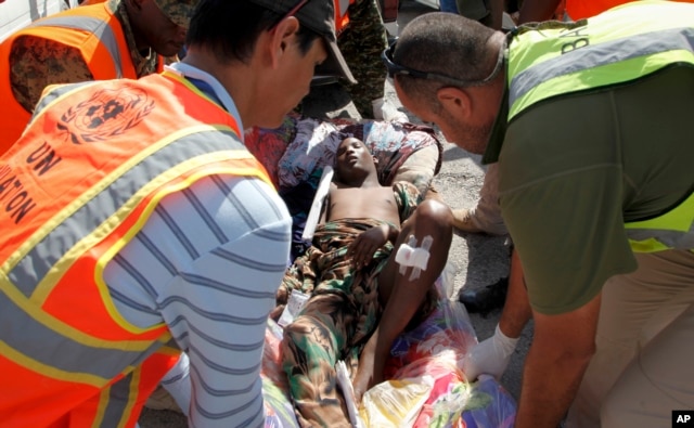 United Nations and other workers assist a young wounded man after he and others were airlifted to Mogadishu for treatment, following Sunday's attack on restaurants in the city of Baidoa, at the airport in Mogadishu, Somalia, Feb. 29, 2016.
