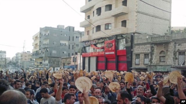 Protesters with pieces of bread shout slogans during a demonstration to show their solidarity with the protesters in Daraa, in the Syrian port city of Banias, May 3, 2011