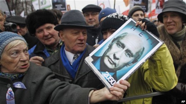 An elderly demonstrator holds a poster showing an edited photo of an aging Prime Minister Vladimir Putin and signed '2050. No'.