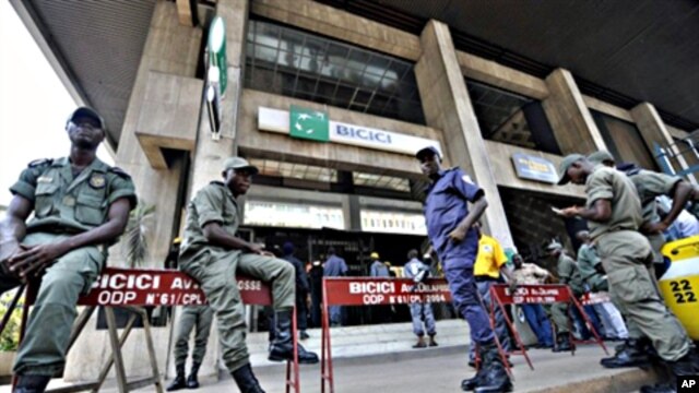 Security contain clients standing outside the headquarters of the Bicici bank as they came to withdraw money in Abidjan, March 3, 2011