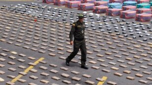 A Colombian police officer walks near packs of confiscated marijuana and cocaine in Cali April 15, 2013. The police confiscated 5.3 tons (10,600 lbs) of marijuana and 877kg (1,933 lbs) of cocaine in the departments of Valle and Cauca during Operation Repu