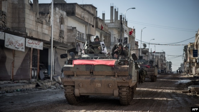 Turkish army vehicles drive on a street in Kobani, Syria, during an operation to relieve the garrison guarding the Suleyman Shah mausoleum in northern Syria, Feb, 22, 2015, 