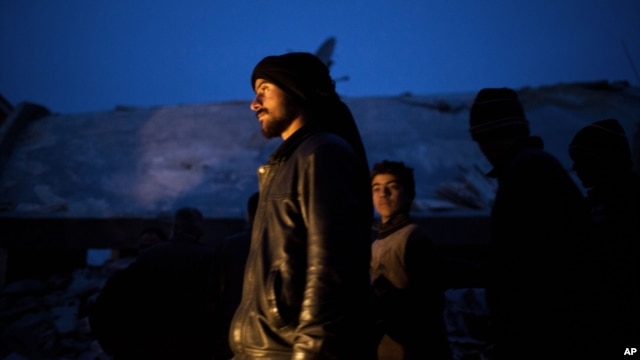 Syrian people seen near a damaged building after it was attacked by a Syrian Army Jet in Azaz, Syria, Sunday, Dec 16, 2012.