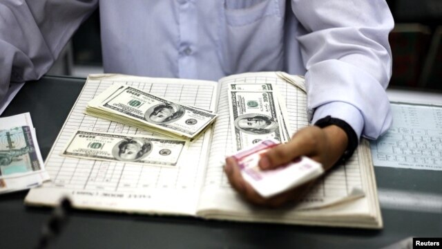 A man counts US dollars and Burma kyats at a money changer in Rangoon, March 21, 2012. 