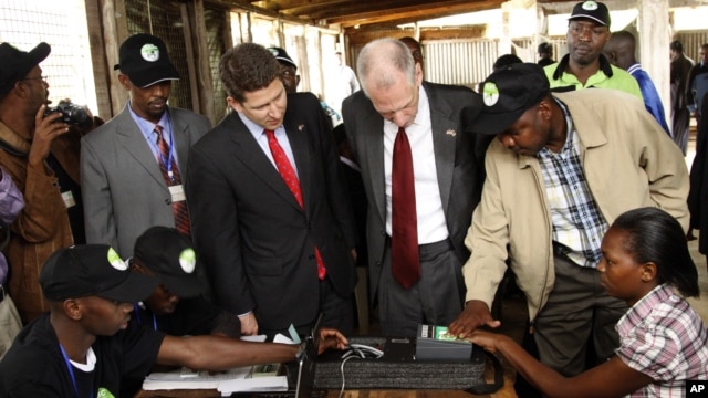 Independent Electoral and Boundaries Commission’s, IEBC, U.S. Ambassador to Kenya, Robert F. Godec, second right and British High Commissioner to Kenya, Christian Turner, second left, inside the voter registration centre in Thika Nairobi Kenya, Dec. 15, 2