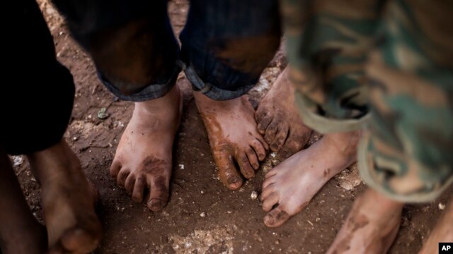 FILE - Displaced Syrian children gather barefoot in a refugee camp near Atma, Idlib province, Syria.