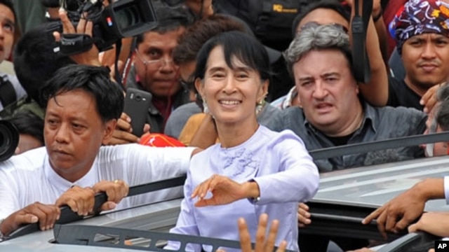 Burma opposition leader Aung San Suu Kyi (C) waves to the crowd as she leaves National League for Democracy (NLD) headquarters after addressing journalists and supporters in Rangoon on April 2, 2012.