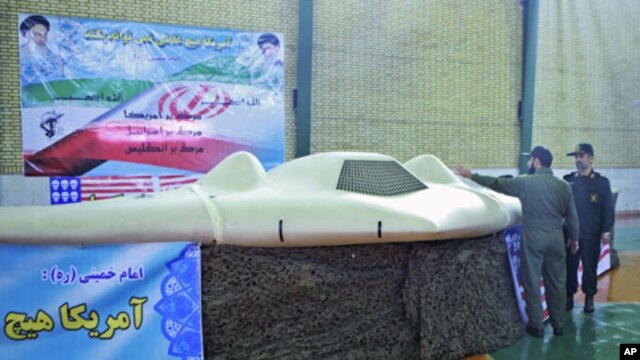 A member of Iran's revolutionary guard points at what Iran says is the U.S. RQ-170 unmanned spy plane, as he speaks with Admiral Hajizadeh (R), a revolutionary guard commander, at an unknown location in Iran, in this undated picture received December 8, 2