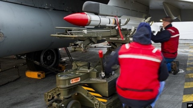 French Navy ordnance crew load a Mica missile under the wing of a Rafale fighter jet aboard France's flagship Charles de Gaulle aircraft carrier, March 25, 2011