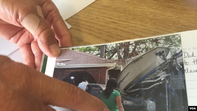 Ông Đỗ Quang Trường chỉ vào một bức hình chụp lại những thiệt hại trước nhà ông sau khi nước rút đi, New Orleans, Louisiana, ngày 29 tháng 8, 2015.