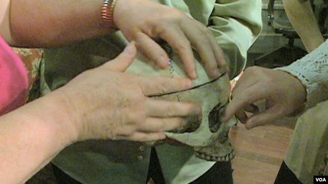 Visually-impaired theatergoers touch the skull, a prop in Everyman Theatre's production of "You Can’t Take It With You."   