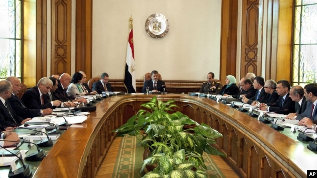 In this image released by the Egyptian Presidency, President Mohammed Morsi, center, meets with his Cabinet including new ministers at the presidential palace in Cairo, January 6, 2013.