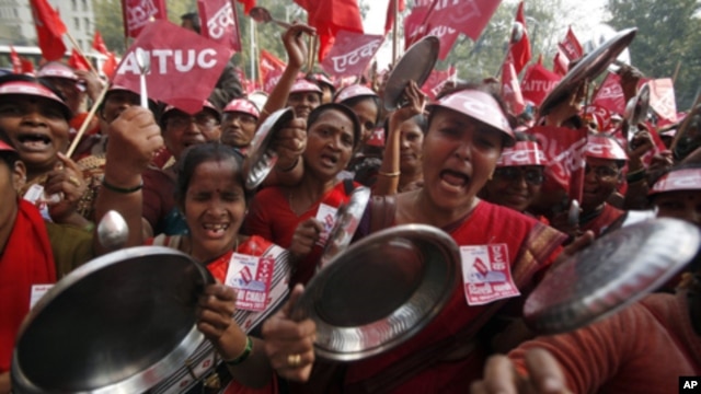 Demonstrators shout slogans as they hold steel plates during a protest against food prices in New Delhi, Feb. 23, 2011.
