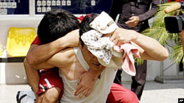 A North Korean man offers a piggy ride to his sick compatriot as they are led from a police cell to an interrogation room at a police station in Pathum Thani province, north of Bangkok. (File)