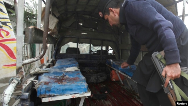 A policeman collects evidence from a police mobile van after it was hit by a bomb blast in Charsadda, on the outskirts of Peshawar, Jan. 22, 2014.