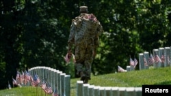Una oficial de la "Vieja Guardia" participa en "Flags-In", un evento anual donde se coloca una pequeña bandera estadounidense frente a las lápidas de miembros del servicio de EE.UU. enterrados en el Cementerio Nacional de Arlington,en Virginia. Foto: Reuters.