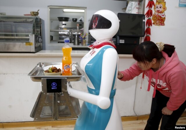 A woman input orders for a robot which works as a waitress in a restaurant in Xi'an, Shaanxi Province, China, April 20, 2016.