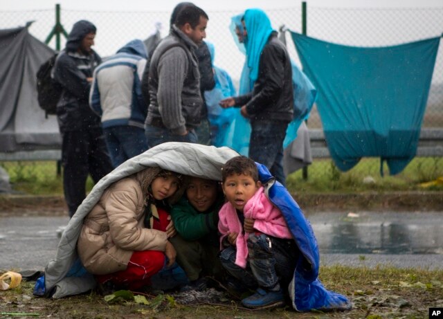 Children take shelter from the rain in Sredisce ob Dravi, a border crossing between Croatia and Slovenia, Oct. 19, 2015.