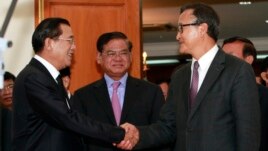 Cambodian Prime Minister Hun Sen, left, shakes hands with opposition party leader Sam Rainsy, right, after a meeting, as Sar Kheng, center, deputy prime minister, looks on at the National Assembly in Phnom Penh, Cambodia, Monday, Sept. 16, 2013. 