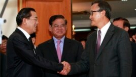 Cambodian Prime Minister Hun Sen, left, shakes hands with opposition party leader Sam Rainsy, right, after a meeting, as Sar Kheng, center, deputy prime minister, looks on at the National Assembly in Phnom Penh, Cambodia, Monday, Sept. 16, 2013. Hun Sen and Sam Rainsy met for the second time on Monday in a bid to resolve a political stalemate, a day after violent clashes on the streets of Phnom Penh. (AP Photo/Heng Sinith)