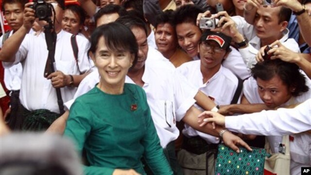 Burma's pro-democracy leader Aung San Suu Kyi greets supporters as she leaves her National League for Democracy party following her meeting with newly elected lawmakers at the party headquarters in Rangoon, April. 7, 2012.
