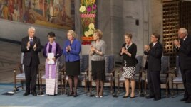 Burmese opposition leader Aung San Suu Kyi, on the podium, second from left, receives standing ovations the Norwegian Nobel Committee her speech at the Peace Nobel Prize lecture at the city hall in Oslo, Saturday, June 16, 2012.