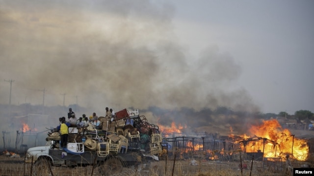 A truck piled with furniture and other items drives past burning businesses and homesteads, locally known as "tukuls", in the center of Abyei, central Sudan in this handout photograph released on May 28, 2011.
