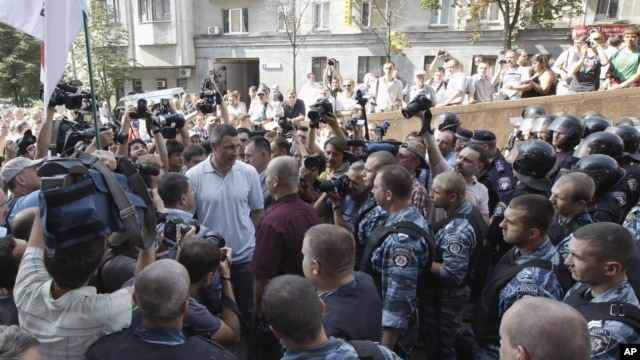 WBC Heavyweight Champion Vitali Klitschko, center in white t-shirt, talks to riot police at an opposition protest rally in front of the Ukrainian House in central Kiev, Ukraine, July 4, 2012.
