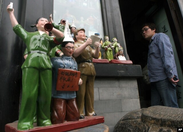 中国陶瓷雕塑再现文革中红卫兵批斗学者的情景，学者胸前的牌子上写着“打倒反动 学术权威”