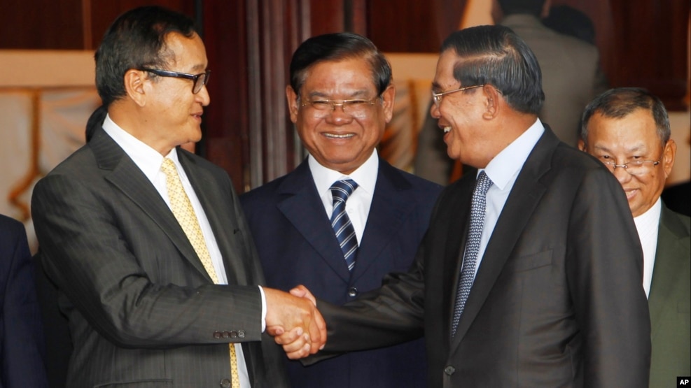 Cambodian Prime Minister Hun Sen, second from right, shakes hands with the main opposition party leader Sam Rainsy, left, of Cambodia National Rescue Party, as Deputy Prime Minister Sar Kheng, second from left, looks on after a meeting in Senate headquarter, Phnom Penh, Cambodia. 