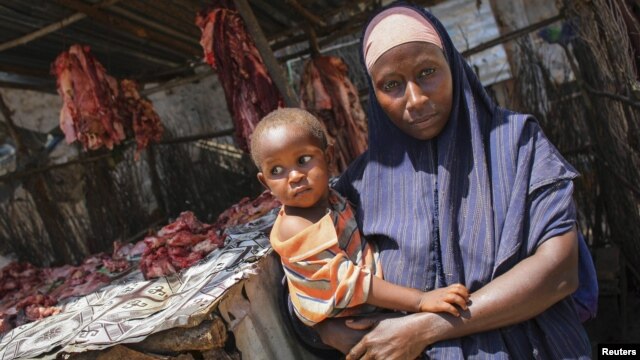 A Somali woman selling meat from a kiosk holds her child in a market area in the centre of the southern Somali port city of Kismayo, October 7, 2012.