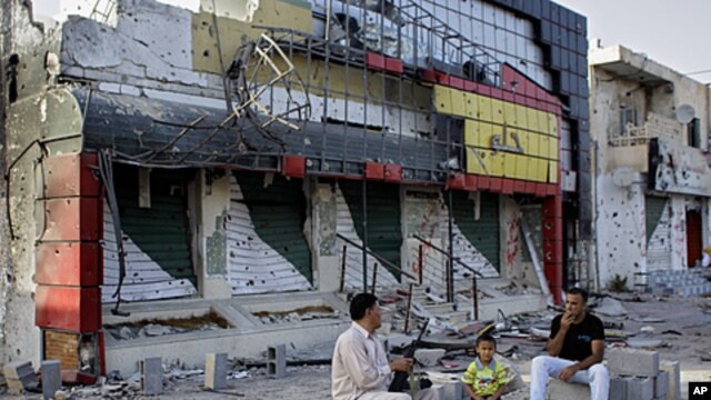 Abdul Basr, 45, center, chats with his neighbor as he sits in front of his damaged pizzeria on Tripoli street in Misrata, Libya, September 2, 2011.