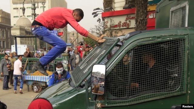 Seorang demonstran melompat ke mobil polisi yang lewat dalam protes anti-pemerintah (22/2). (Foto: Reuters)