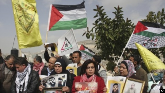 Palestinians hold flags and photographs during a protest in solidarity with Adnan, and for the release of Palestinian prisoners held in Israeli prisons, in the West Bank city of Nablus, February 8, 2012.