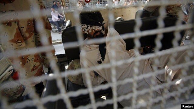 A blindfolded man sits in a Pakistani rangers' vehicle after being arrested for inciting unrest in a residential area in Karachi, December 26, 2012.