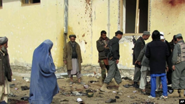 Afghans stand at the site of a suicide attack in Emam Saheb district of Kunduz province February 21, 2011